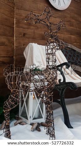 A metallic deer with a garland stands on artificial  snow near a bench. New Year decor. Christmas