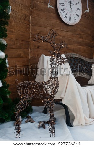 A metallic deer with a garland stands on artificial  snow near a bench. New Year decor. Christmas