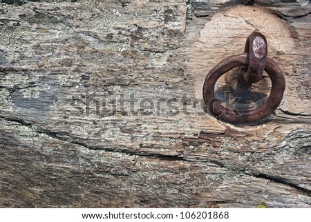 Aged metal rope anchor embedded into old rock used as a background