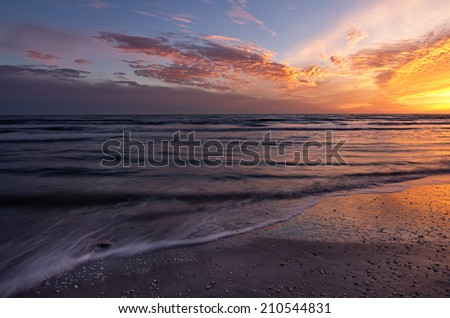 Waves slowly retreat from a beach at sunset