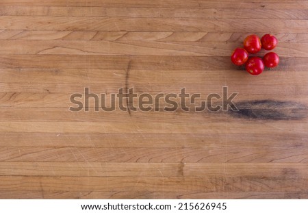 Cherry tomatoes sit on a worn butcher block counter