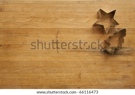 A view looking down on a metal star and tree cookie cutter on a worn butcher block cutting board