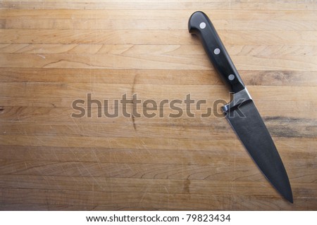 A knife sits to the side of a butcher block counter top