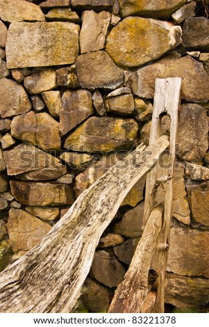A wooden split rail fence ends at a stone rock wall