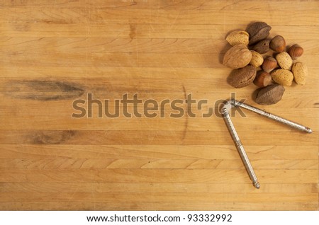 Mixed nuts sit on a butcher block counter with a metal nutcracker