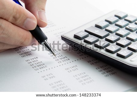 Analyzing finance report with calculator and pen