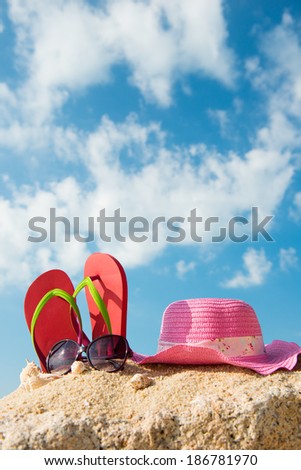 Red flip flop, sunglasses and floppy hat at the beach