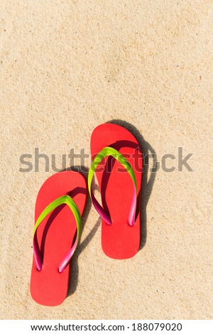 Summer theme with red flip flop on sandy beach