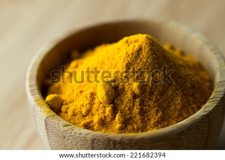 Close up of turmeric powder in wooden bowl