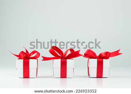 Three gift boxes with red ribbons on white background