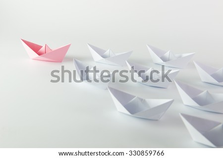 Woman leadership concept with pink paper ship leading among white