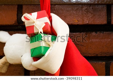 Gift boxes with ribbon in a Christmas sock hanging on fireplace mantel