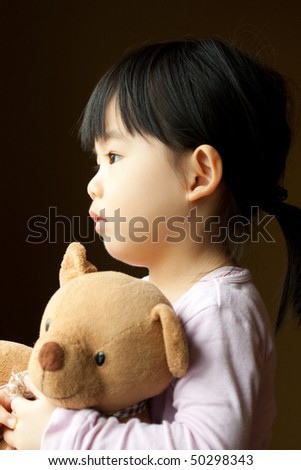 Sad little girl holds a teddy bear looks into the window. Resentment and expectation