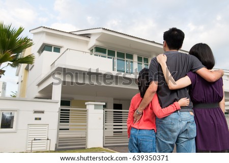 Parents and kid standing in front of dream house in modern residential houses