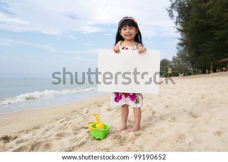 Little child girl holds a white board at beach