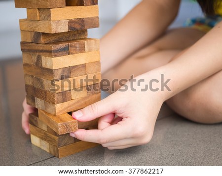Closeup of asian kid\'s hand playing wood blocks stack game