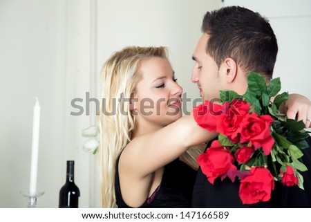 Love - a beautiful tender moment between a young man and his pretty blond girlfriend as she accepts his proposal for her hand in marriage - stock photo