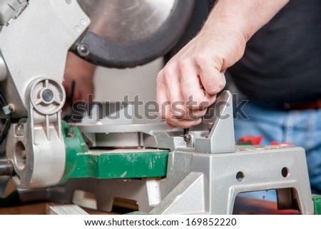 A man is adjusting a metal saw.