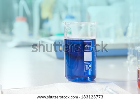 A single big beaker filled with a blue liquid in a laboratory.