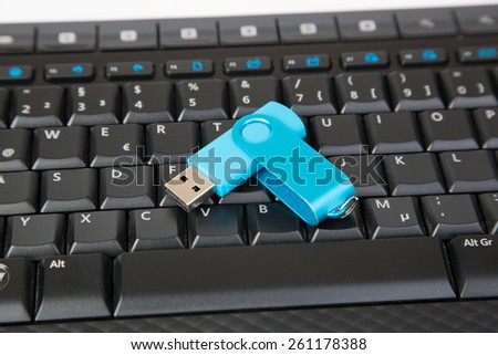 An USB Stick is laying on a black Keyboard.