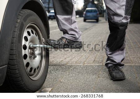 A man is loosening the screws from the tire.