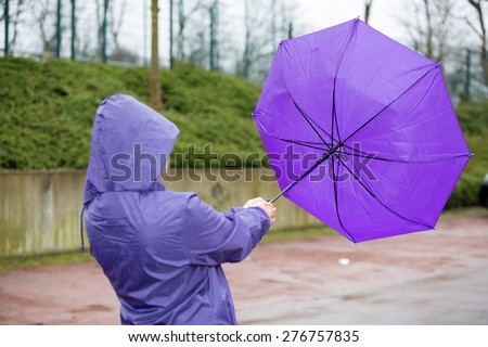A people is fighting with an umbrella in the wind.