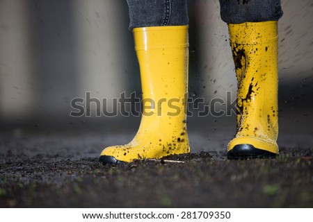 A pair of yellow rubber boots in a dirty puddle