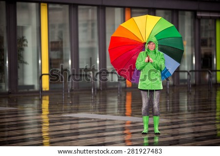 A woman is waiting in the rain with her rain cloth.