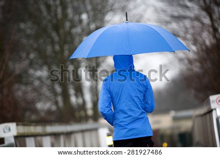 A man is walking in the rain with his umbrella and raincoat.