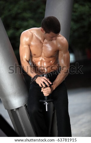 A Bodybuilder is training the upper part of his body a short dumbbell