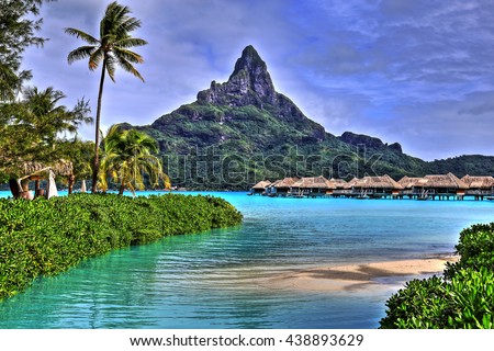 View on Mount Otemanu through turquoise lagoon, palms, and overwater bungalows on the tropical island Bora Bora, honeymoon destination, near Tahiti, French Polynesia, Pacific ocean.\
HDR picture.