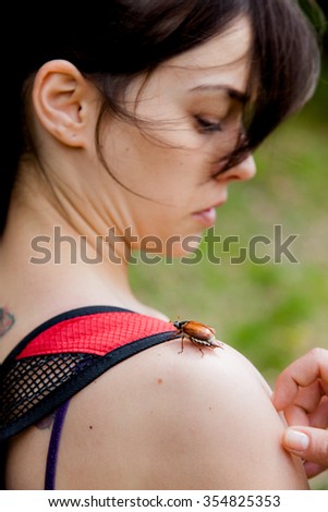 Girl surprised by may beetle on her shoulder