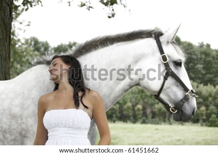 beautiful teenager day dreaming against a horse in field