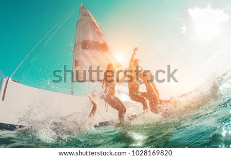 Happy crazy friends diving from sailing boat into the sea - Young people jumping inside ocean in summer vacation - Main focus on center man - Travel and fun concept - Fisheye lens distortion