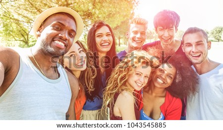 Happy friends taking selfie at bbq picnic in nature park with back sunlight - Young people having fun with trends technology - Youth lifestyle, tech and friendship concept - Focus on african man face