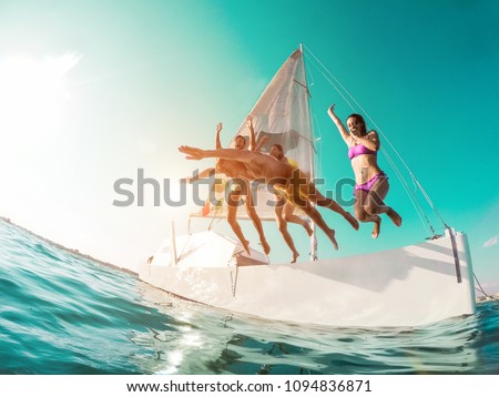 Happy crazy friends diving from sailing boat into the sea - Young people jumping inside ocean in summer vacation - Main focus on right girl body - Travel and fun concept - Fisheye lens distortion