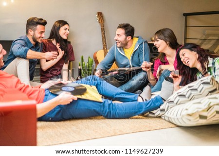 Happy friends doing party listening vintage vinyl disc albums - Young millennials people having fun drinking shots and laughing together - Youth and winter fest concept - Focus on right man face