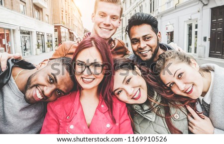 Happy friends from diverse cultures and races taking selfie with back lighting - Youth, millennial generation and friendship concept with young people having fun together - Main focus on left two guys