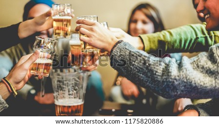 Happy friends cheering with half pints beer in pub restaurant - Young people having fun at chalet bar party - Youth, vacation and nightlife lifestyle concept - Focus on close-up hands