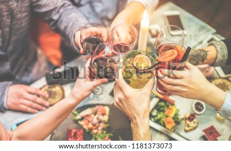 Group of trendy friends enjoying appetizer in american bar - Young people hands cheering with wine and tropical fruits cocktails - Radial purple and green filters editing - Focus on right hand glass