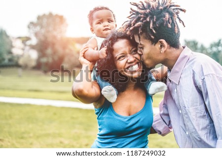 Happy african family having fun outdoor during sunny day in public park - Dad, mum and daughter enjoying tender moments together - Love and parenthood concept - Main focus on woman face