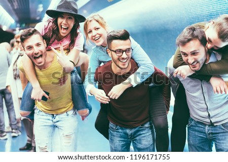 Group of friends having fun in underground metropolitan station - Young people hanging out ready for party night - Friendship and youth lifestyle concept - Focus on center girl face