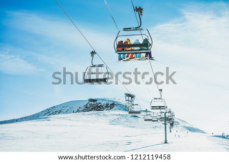 People on ski lift in winter ski resort - Holidays, snow gear renting, skiing, snowboarding and mountain landscape concept - Focus on guys sitting in cable car