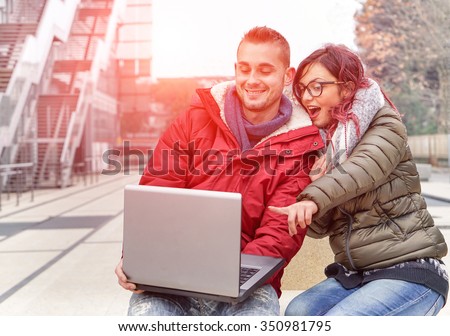 Best friends with computer laptop looking surprised - Young students using pc online outdoors in city  - Technology and friendship concept in urban contest - Vintage filter with artificial sunlight