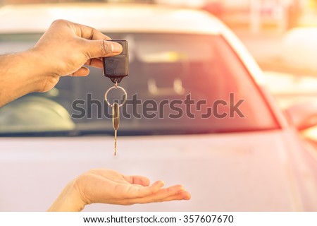Indian man giving modern car keys ready for rental - Concept of transportation with automobile second hand sale and trade - Warm filtered look with artificial sunlight - Focus on hand keys