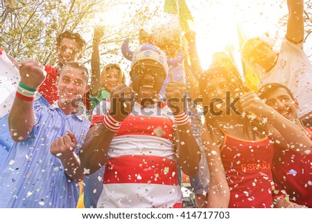 Multinational football supporters celebrating a goal in bar restaurant outdoors - Happy multiracial people having fun for olympic games - Sport against racism concept - Soft warm filter