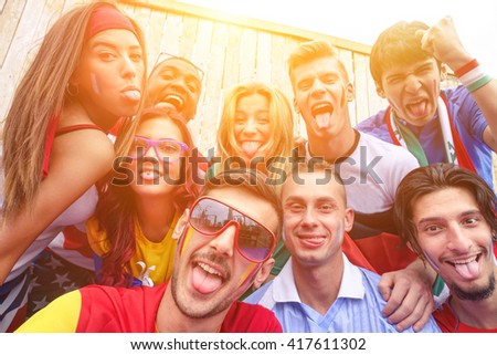 Multinational football supporters taking selfie outdoors - Happy multiracial people making funny faces on camera for olympic games - Sport against racism concept - Focus on bottom left guy