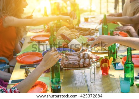 Group of multiracial students having barbecue on a sunny day - Young cheerful people eating meat on summer time - Concept about good and positive mood with friends - Focus on sausages