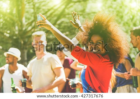 Multiracial young people dancing in forest party in summer time - Cheerful multi ethnic friends drinking outdoor - New music entertainment trends  - Focus on black girl - Vintage retro editing