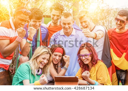 Diverse mix of friends sports fans watching football match on tablet outdoor - Celebrating winning goal huddled on couch shouting excited - Sport against racism concept - Main focus on blond girl